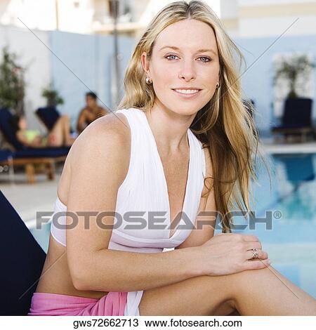 Portrait of a young woman sitting on a lounge chair at the poolside View Large Photo Image Stock Image - Portrait of a young woman sitting on a lounge chair at the poolside. Fotosearch