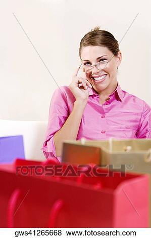 Portrait of a young woman sitting with shopping bags View Large Photo Image Stock Photo - Portrait of a young woman sitting with shopping bags. Fotosearch