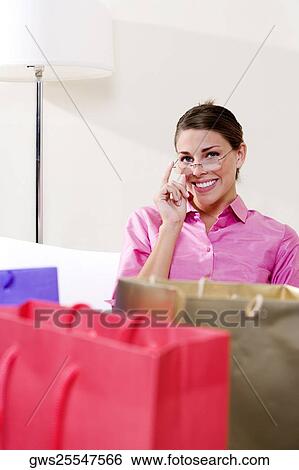 Stock Photograph - Portrait of a young woman sitting with shopping bags. Fotosearch