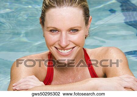Stock Image - Portrait of a young woman smiling in a swimming pool. Fotosearch