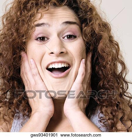 Portrait of a young woman smiling with her hands on her face View Large Photo Image Stock Image - Portrait of a young woman smiling with her hands on her face. Fotosearch