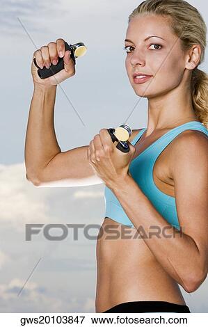 Portrait of a young woman squeezing hand grips View Large Photo Image Stock Photo - Portrait of a young woman squeezing hand grips. Fotosearch