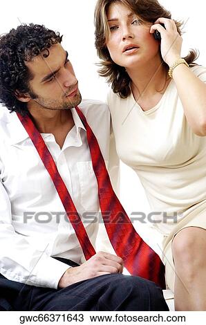 Stock Image - Portrait of a young woman talking on a mobile phone with a young man sitting beside her. Fotosearch