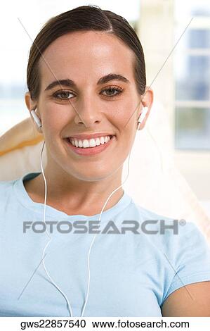 Stock Image - Portrait of a young woman wearing headphones listening to music. Fotosearch