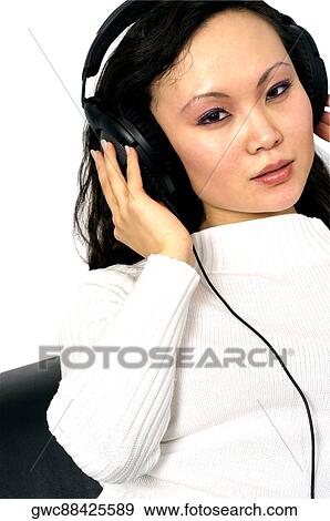Stock Photo - Portrait of a young woman wearing headphones listening to music. Fotosearch