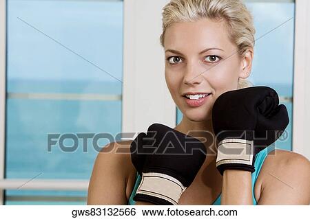 Stock Photograph - Portrait of a young woman wearing boxing gloves. Fotosearch
