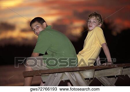 Portrait of two boys sitting on a picnic table View Large Photo Image Stock Image - Portrait of two boys sitting on a picnic table. Fotosearch