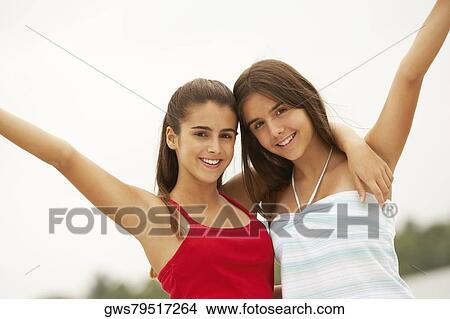 Picture - Portrait of two girl smiling with their hands raised. Fotosearch