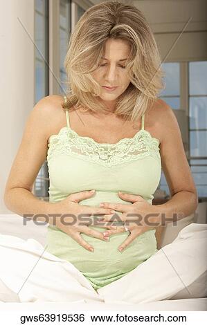 Stock Photograph - Pregnant mid adult woman touching her abdomen. Fotosearch
