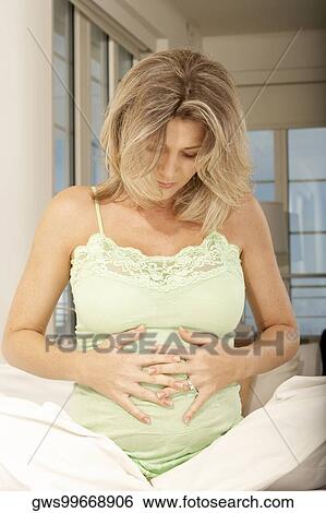 Pregnant mid adult woman touching her abdomen View Large Photo Image Stock Photograph - Pregnant mid adult woman touching her abdomen. Fotosearch