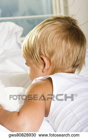 Rear view of a boy lying on the bed View Large Photo Image Stock Image - Rear view of a boy lying on the bed. Fotosearch