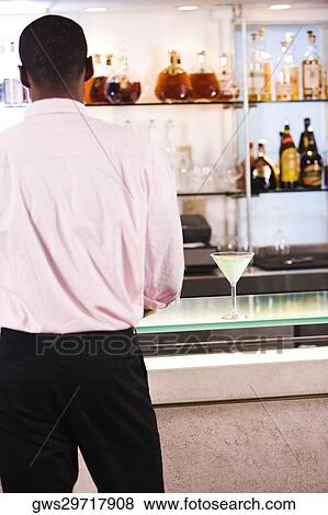 Rear view of a businessman standing at a bar counter View Large Photo Image Stock Photo - Rear view of a businessman standing at a bar counter. Fotosearch