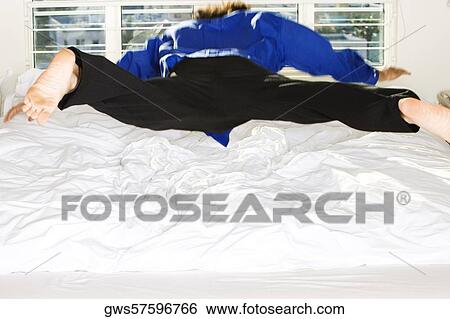 Rear view of a mid adult man jumping on the bed View Large Photo Image Stock Photograph - Rear view of a mid adult man jumping on the bed. Fotosearch