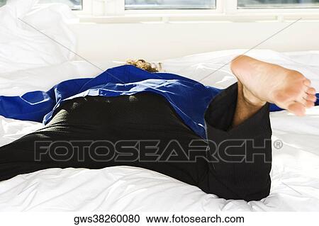 Rear view of a mid adult man lying on the bed View Large Photo Image Stock Image - Rear view of a mid adult man lying on the bed. Fotosearch