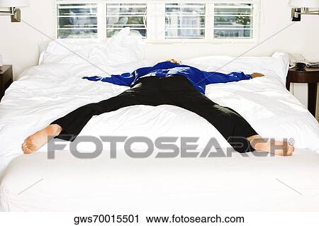 Stock Image - Rear view of a mid adult man lying on the bed. Fotosearch