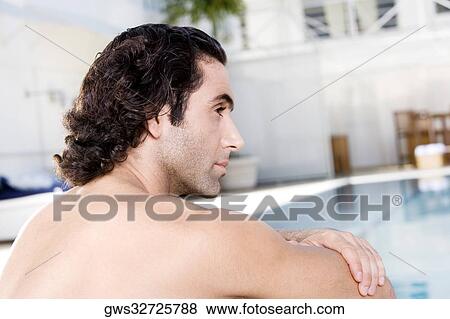 Rear view of a mid adult man sitting at the poolside View Large Photo Image Stock Photo - Rear view of a mid adult man sitting at the poolside. Fotosearch