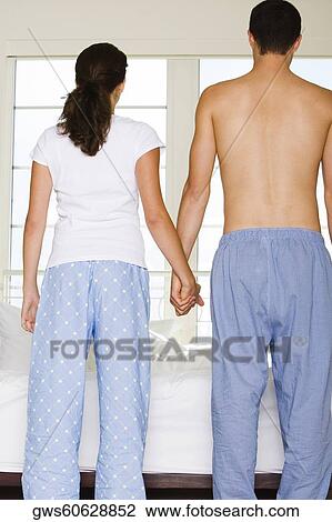 Rear view of a young couple holding hands View Large Photo Image Stock Image - Rear view of a young couple holding hands. Fotosearch
