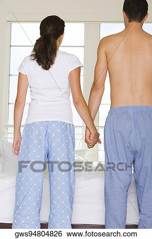 Rear view of a young couple holding hands View Large Photo Image Stock Photograph - Rear view of a young couple holding hands. Fotosearch