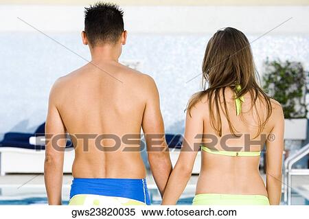 Rear view of a young couple standing at the poolside View Large Photo Image Stock Photography - Rear view of a young couple standing at the poolside. Fotosearch