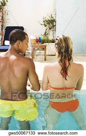 Rear view of a young couple standing in a swimming pool View Large Photo Image Stock Image - Rear view of a young couple standing in a swimming pool. Fotosearch