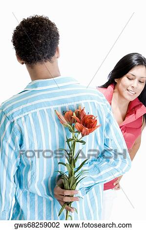 Rear view of a young man hiding flowers behind his back View Large Photo Image Stock Image - Rear view of a young man hiding flowers behind his back. Fotosearch