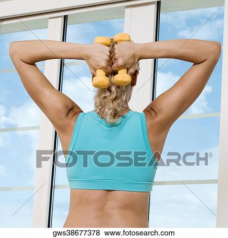 Rear view of a young woman exercising with dumbbells View Large Photo Image Stock Photo - Rear view of a young woman exercising with dumbbells. Fotosearch
