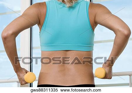 Stock Photography - Rear view of a young woman exercising in a gym. Fotosearch