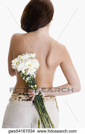 Rear view of a young woman hiding a bunch of flowers behind her back View Large Photo Image Picture - Rear view of a young woman hiding a bunch of flowers behind her back. Fotosearch