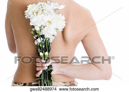 Picture - Rear view of a young woman hiding a bunch of flower behind her back. Fotosearch