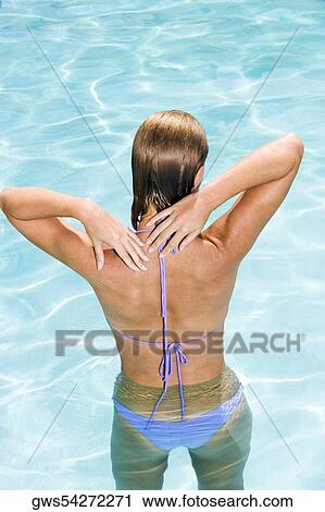 Stock Image - Rear view of a young woman in a swimming pool. Fotosearch
