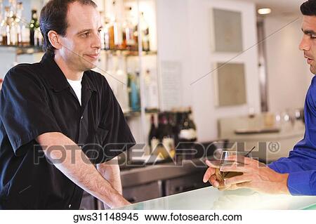 Side profile of a businessman and a bartender at a bar counter View Large Photo Image Stock Photography - Side profile of a businessman and a bartender at a bar counter. Fotosearch