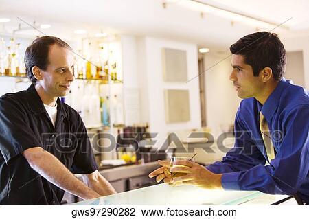 Side profile of a businessman holding a glass talking to a bar tender View Large Photo Image Stock Image - Side profile of a businessman holding a glass talking to a bar tender. Fotosearch