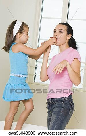 Side profile of a girl feeding her mother View Large Photo Image Stock Photograph - Side profile of a girl feeding her mother. Fotosearch