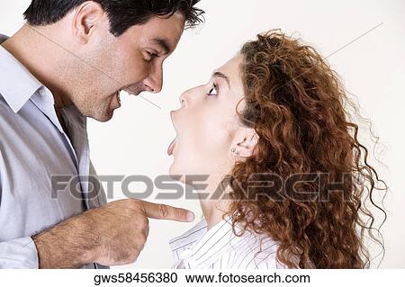Stock Image - Side profile of a mid adult man and a young woman arguing. Fotosearch