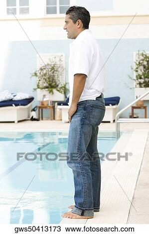 Stock Image - Side profile of a mid adult man standing at the poolside. Fotosearch