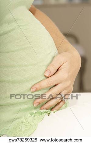 Side profile of a pregnant woman touching her abdomen View Large Photo Image Stock Photography - Side profile of a pregnant woman touching her abdomen. Fotosearch
