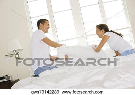 Side profile of a young couple having a pillow fight View Large Photo Image Stock Photo - Side profile of a young couple having a pillow fight. Fotosearch