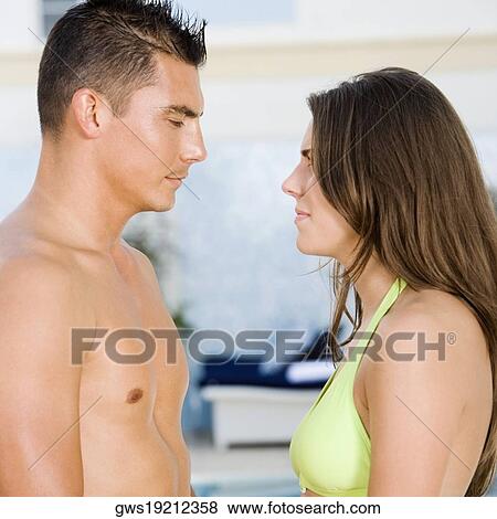 Side profile of a young couple looking at each other at the poolside View Large Photo Image Stock Photo - Side profile of a young couple looking at each other at the poolside. Fotosearch