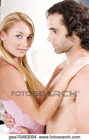 Picture - Side profile of a young couple embracing each other. Fotosearch