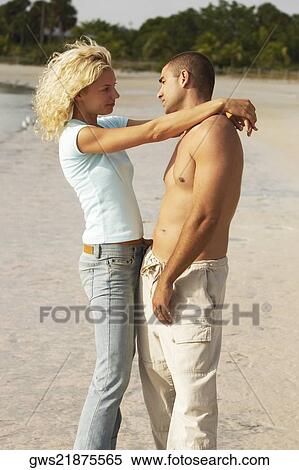 Stock Photography - Side profile of a young couple standing and looking at each other. Fotosearch