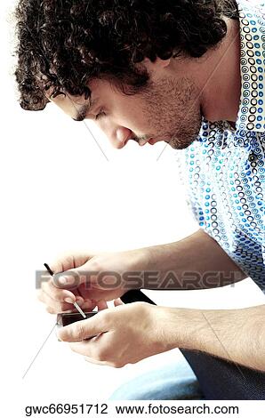 Side profile of a young man operating a personal data assistant View Large Photo Image Stock Image - Side profile of a young man operating a personal data assistant. Fotosearch