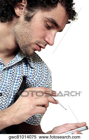Stock Photography - Side profile of a young man operating a personal data assistant. Fotosearch