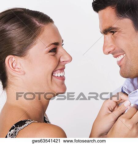 Side profile of a young woman buttoning the shirt of a mid adult man View Large Photo Image Stock Image - Side profile of a young woman buttoning the shirt of a mid adult man. Fotosearch