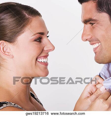 Side profile of a young woman buttoning the shirt of a mid adult man View Large Photo Image Stock Photograph - Side profile of a young woman buttoning the shirt of a mid adult man. Fotosearch