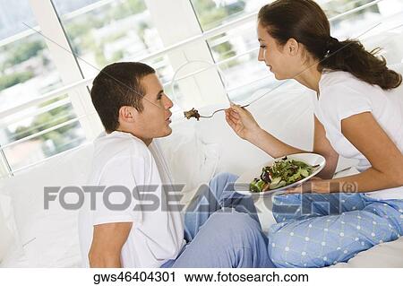 Side profile of a young woman feeding a young man salad View Large Photo Image Stock Image - Side profile of a young woman feeding a young man salad. Fotosearch