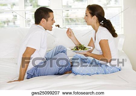 Side profile of a young woman feeding a young man salad View Large Photo Image Stock Photo - Side profile of a young woman feeding a young man salad. Fotosearch