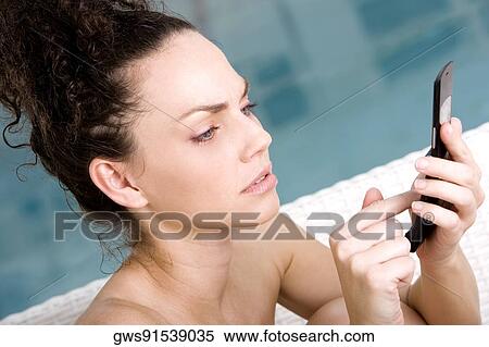 Side profile of a young woman holding a mobile phone View Large Photo Image Stock Photography - Side profile of a young woman holding a mobile phone. Fotosearch