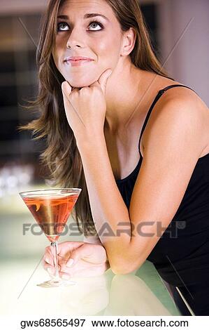 Stock Photo - Side profile of a young woman leaning over a bar counter. Fotosearch