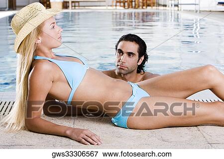 Side profile of a young woman lying down at the poolside with a mid adult man in the swimming pool View Large Photo Image Stock Photo - Side profile of a young woman lying down at the poolside with a mid adult man in the swimming pool. Fotosearch