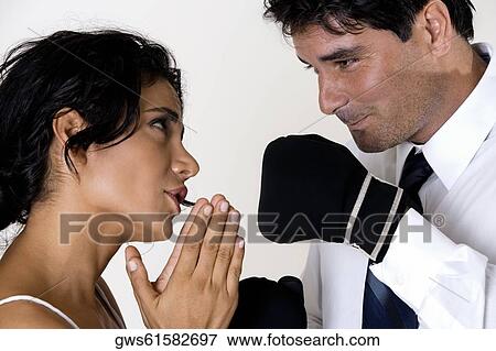 Side profile of a young woman pleading before a mid adult man wearing boxing gloves View Large Photo Image Stock Photo - Side profile of a young woman pleading before a mid adult man wearing boxing gloves. Fotosearch